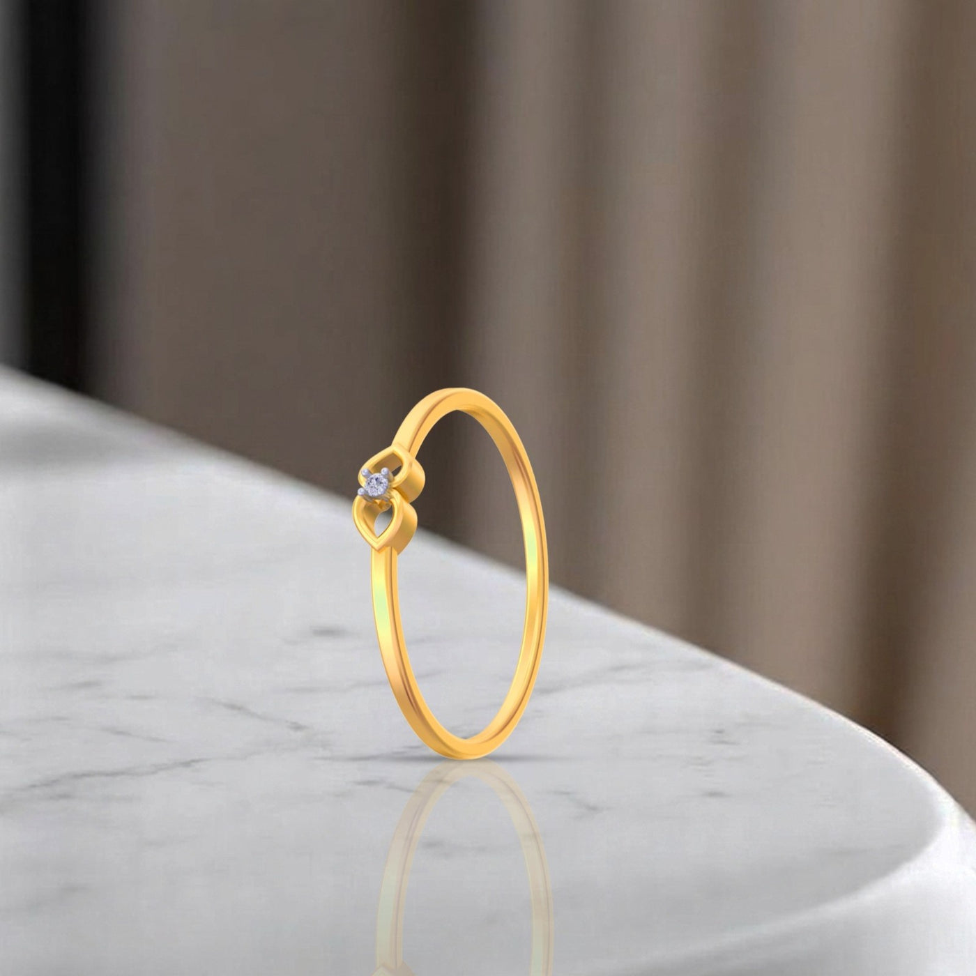 Gold ring with a leaf design on a marble surface