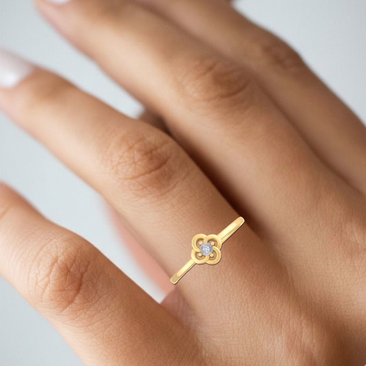 Gold and diamond with floral-design on a person's finger.