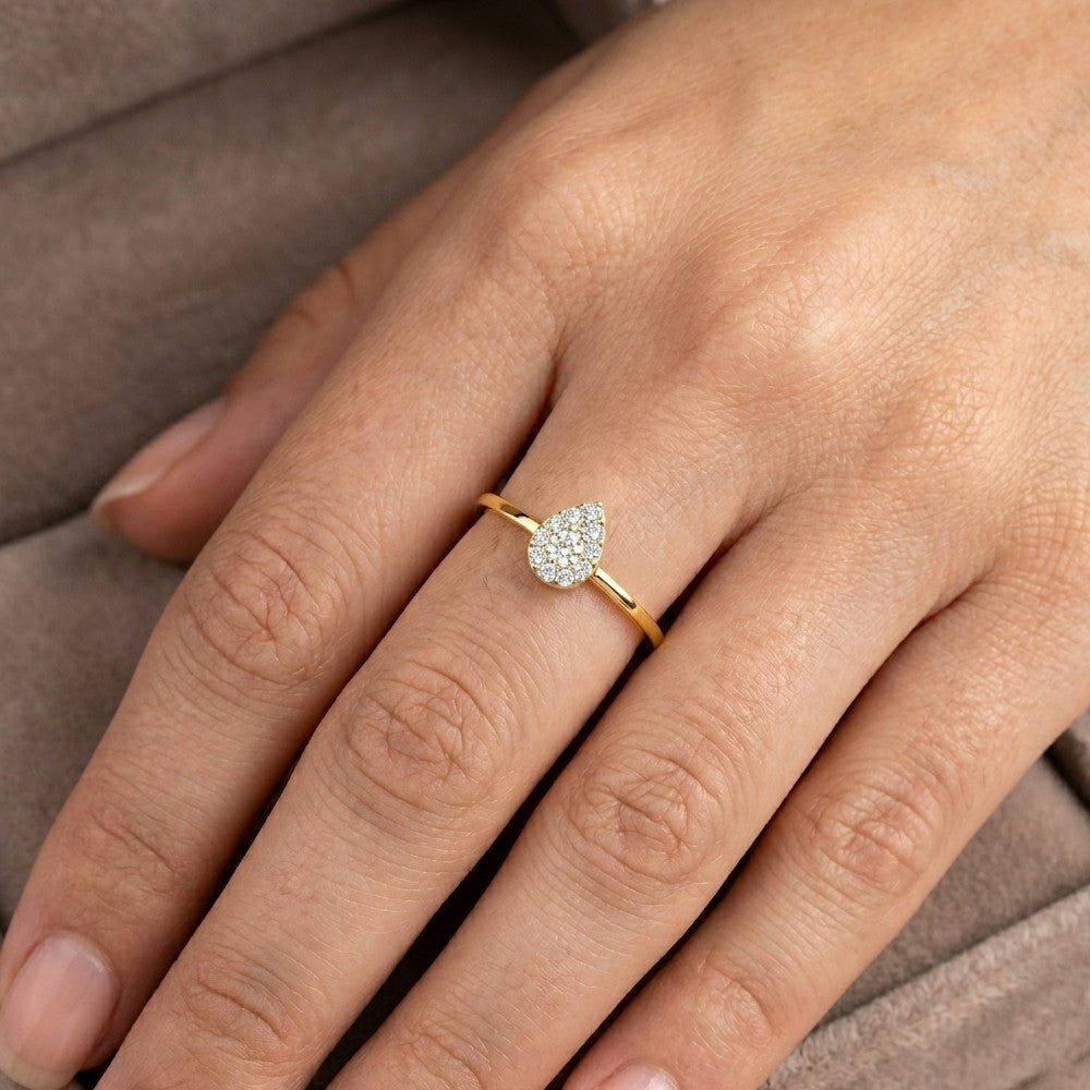 A close-up of a hand wearing a gold and diamond ring with a teardrop-shaped center cluster ring.