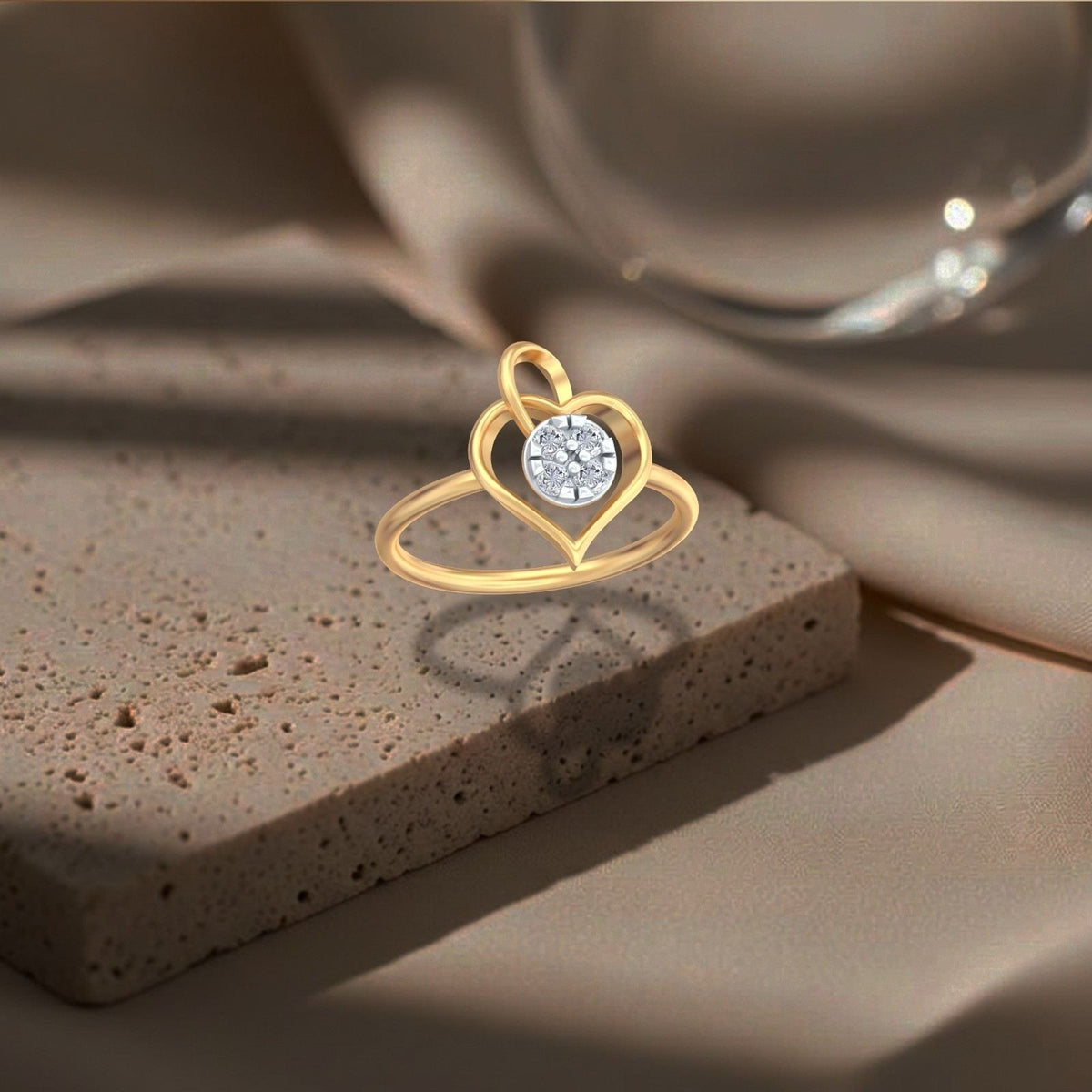 A gold and diamond ring featuring a heart design with a central round cluster,  shown on a brown surface.