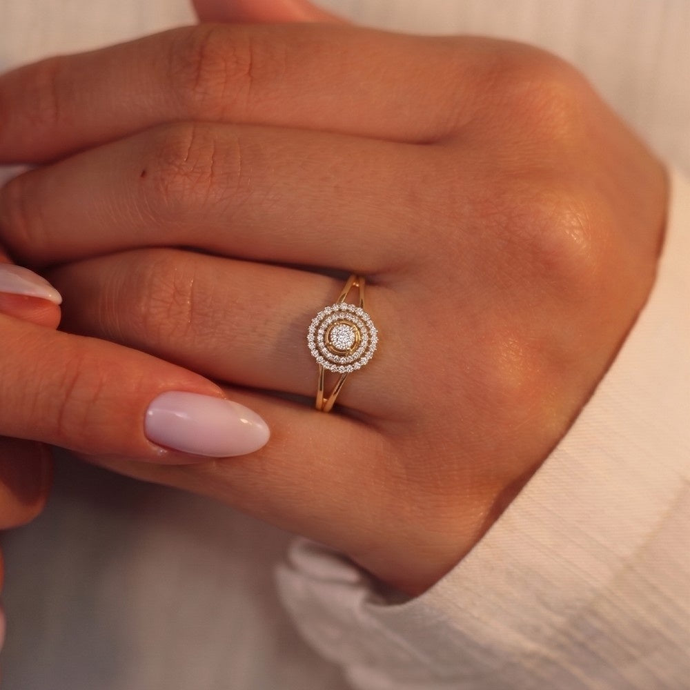 Close-up of a hand wearing a gold ring with diamonds on a neutral background
