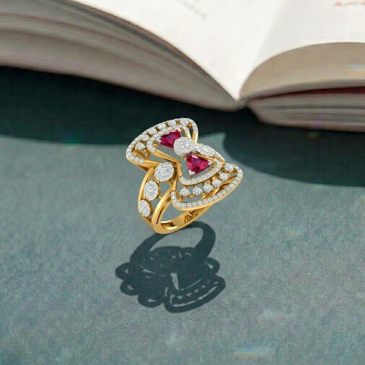 Gold ring with ruby gemstones and diamond accents on a gray surface.