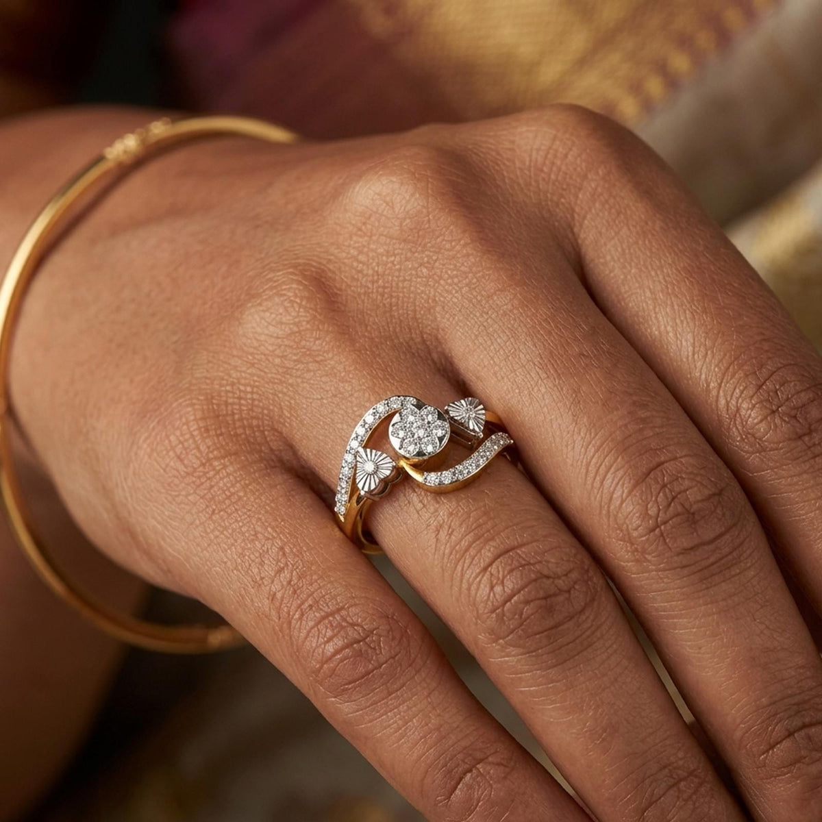 Gold ring with a diamond design on a hand against a saree background
