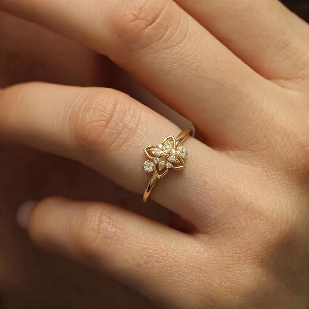 Gold and diamond ring with floral design on a hand.