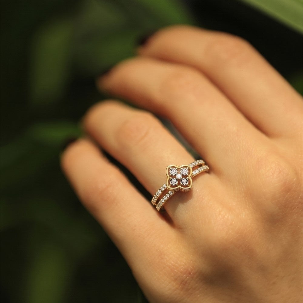 Gold ring with diamonds on a person's finger against a blurred green background.