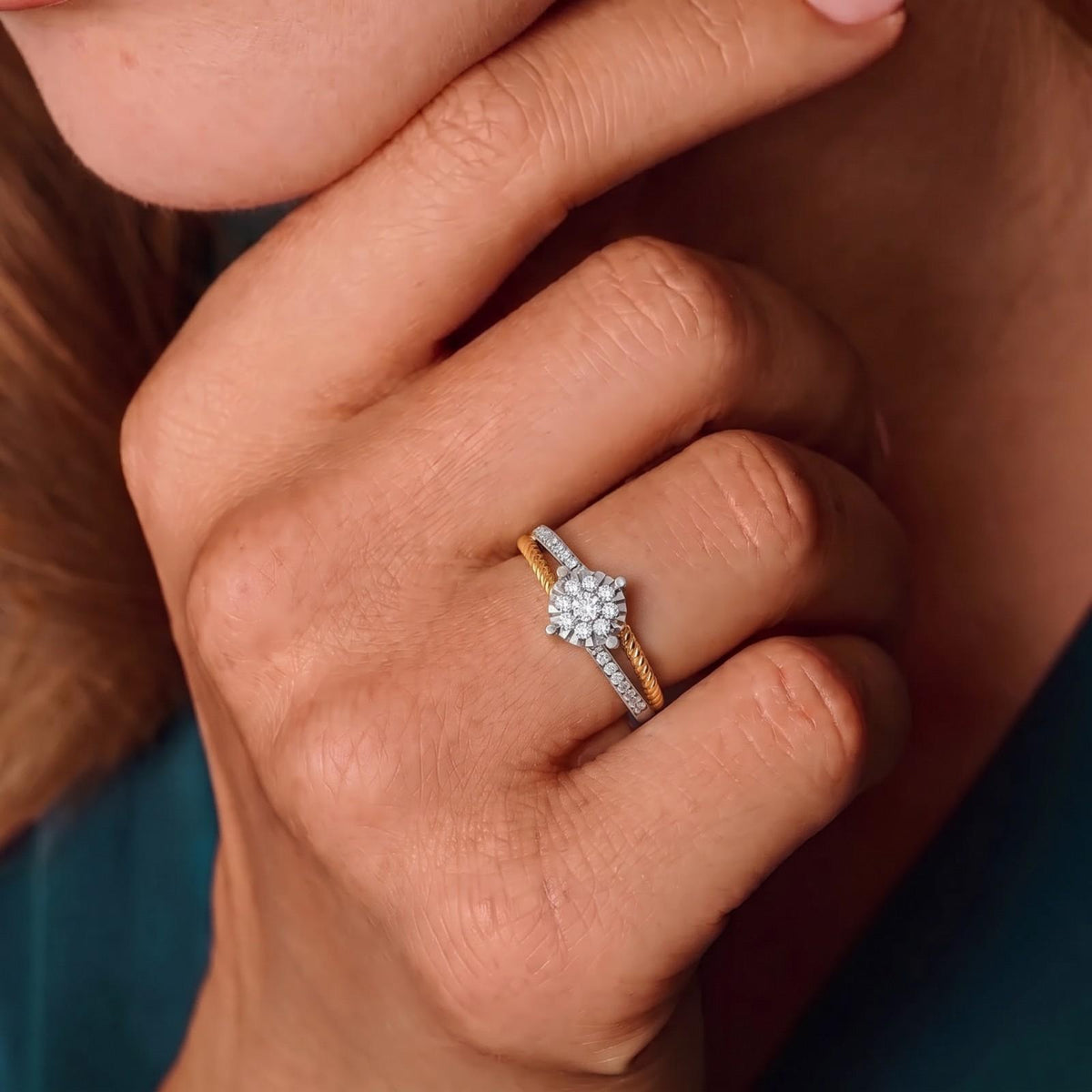 Close-up of a hand wearing a gold and diamond ring on a neutral background