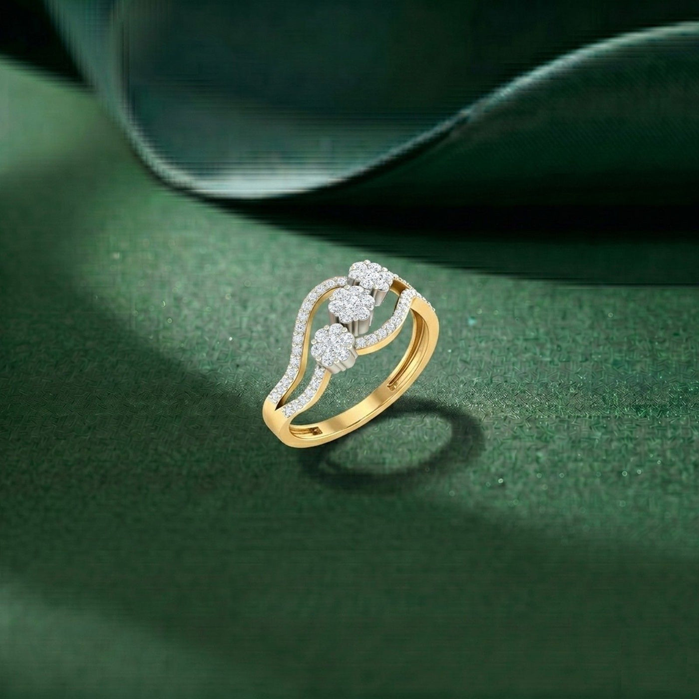 A gold ring featuring a diamond-encrusted floral design, displayed on a textured dark green surface.