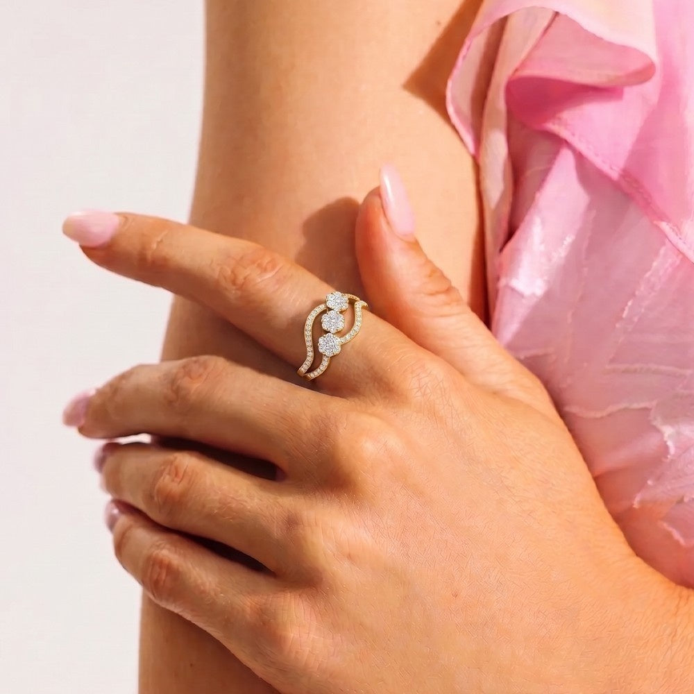 Hand wearing a decorative ring with a pink garment in the background.
