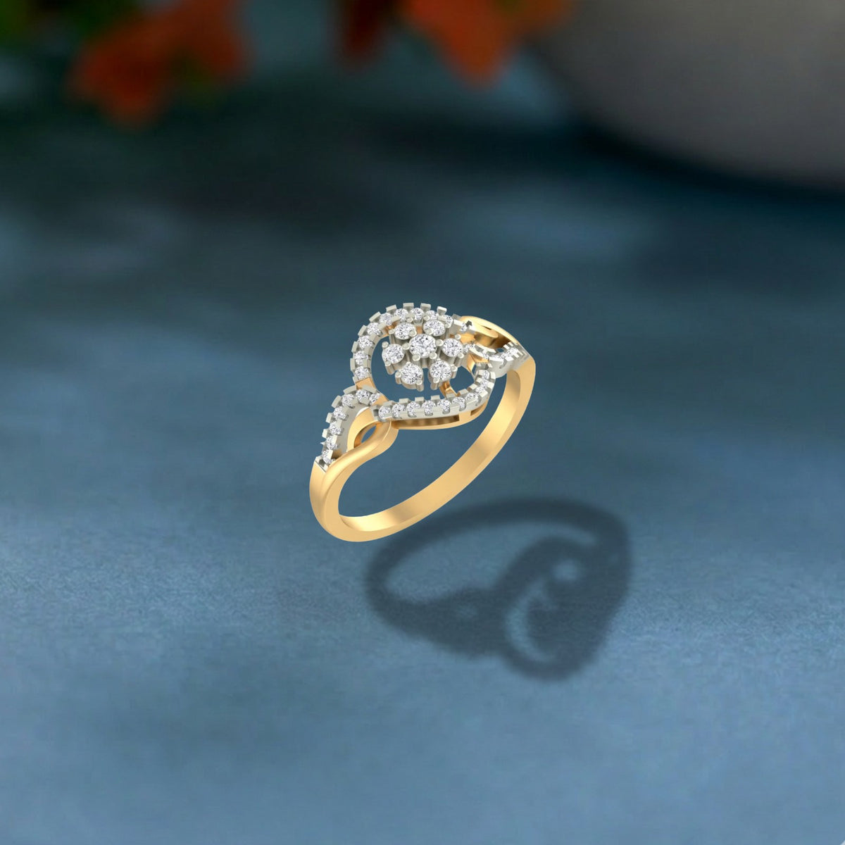 Gold and diamond with floral design ring on a pink surface.