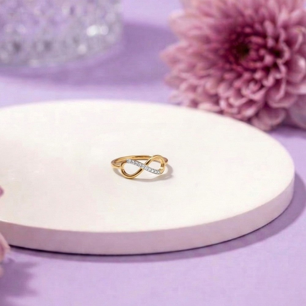 Gold ring with diamonds on a white stand with a pink flower in the background