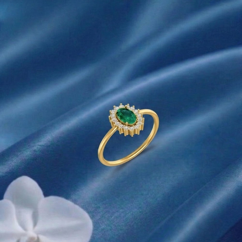 Gold ring with a emerald gemstone on a blue fabric background