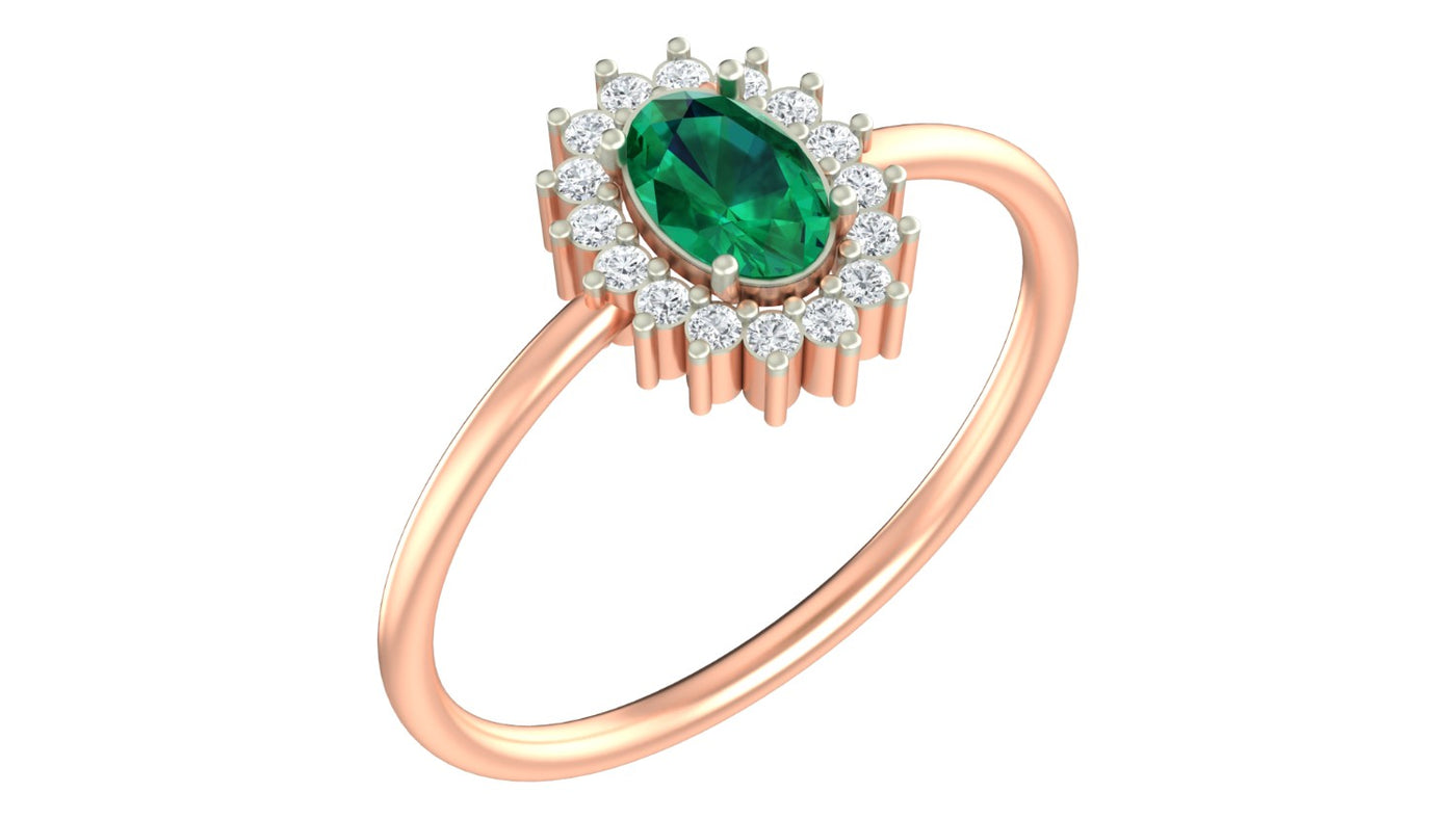 A rose gold ring featuring a emerald gemstone center stone surrounded by a halo of small clear stones, set on a plain white background.