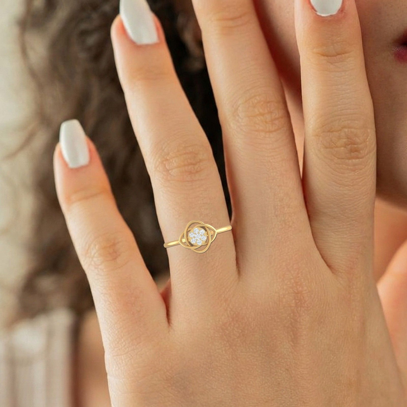 Gold ring with a diamond on a person's finger against a blurred background