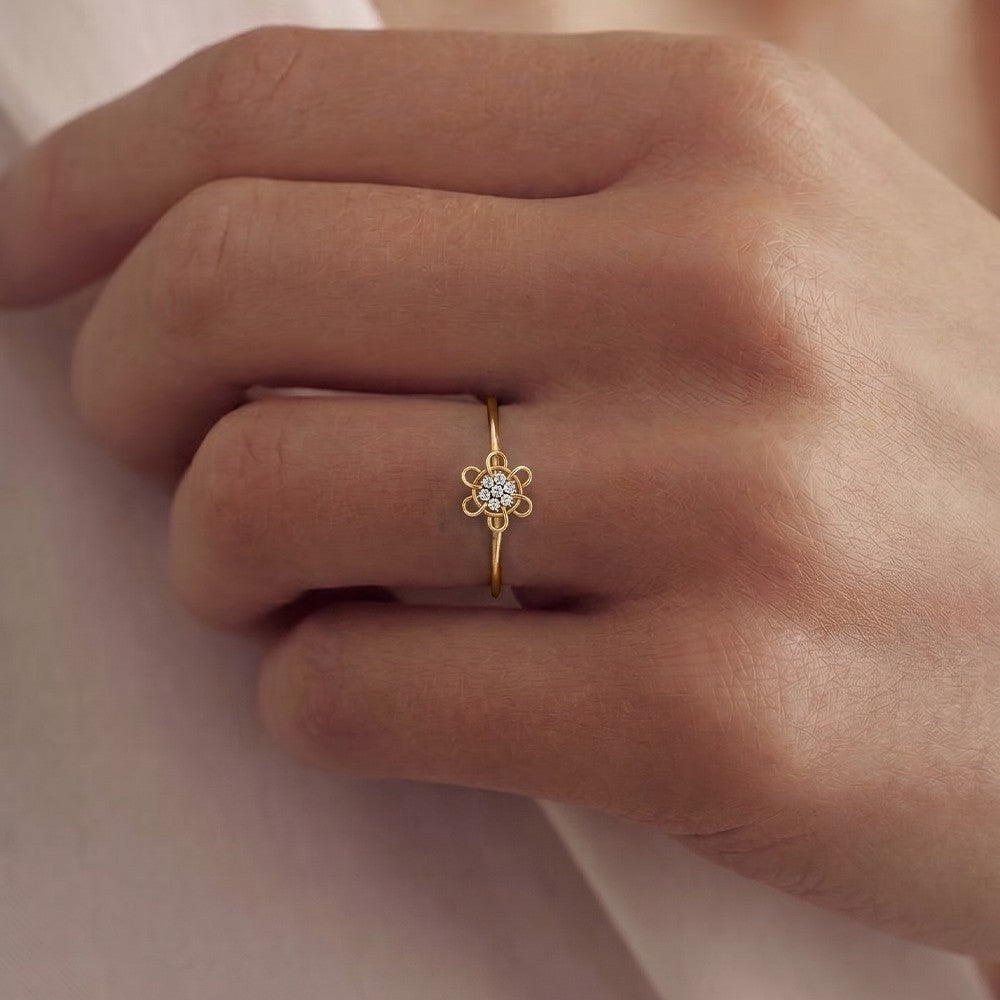 Gold ring with a diamond on a person's finger against a neutral background