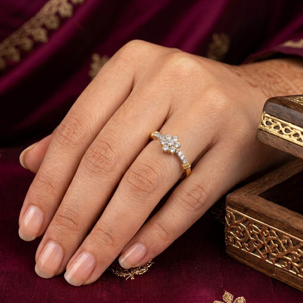 A delicate gold ring with a small white floral center, worn on a woman's ring finger.