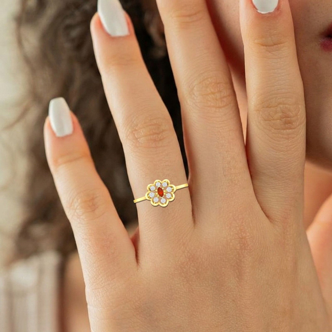 Gold ring with a red gemstone on a hand against a blurred background