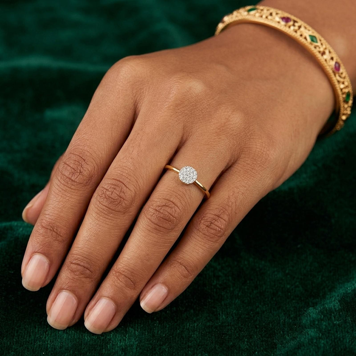 Gold ring with a diamond on a person's finger against a green fabric background
