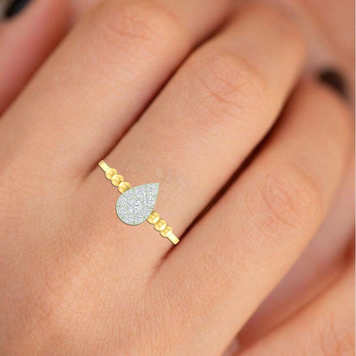 Gold and diamond ring with a teardrop-shaped cluster on a finger