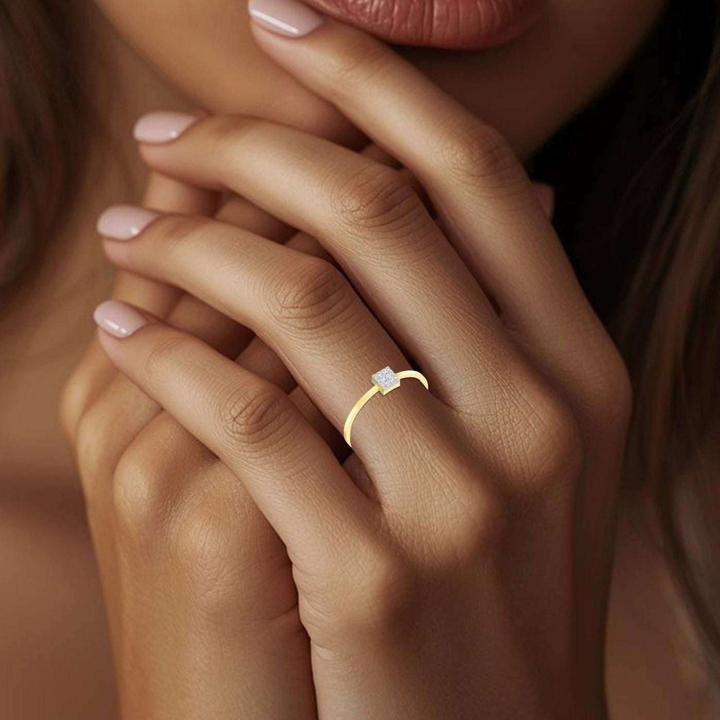 Close-up of a hand wearing a gold ring with a diamond on a blurred background