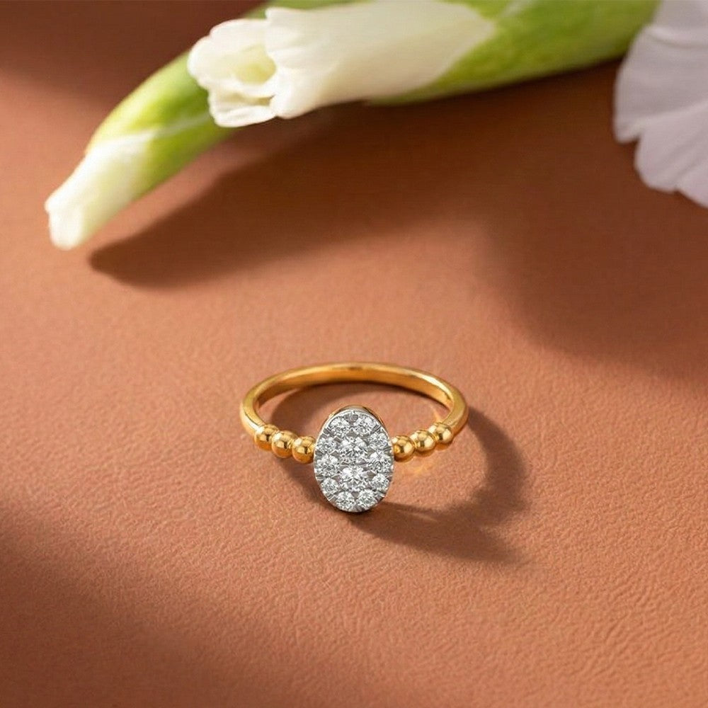 Gold ring with diamond accents on a brown surface with a white flower.