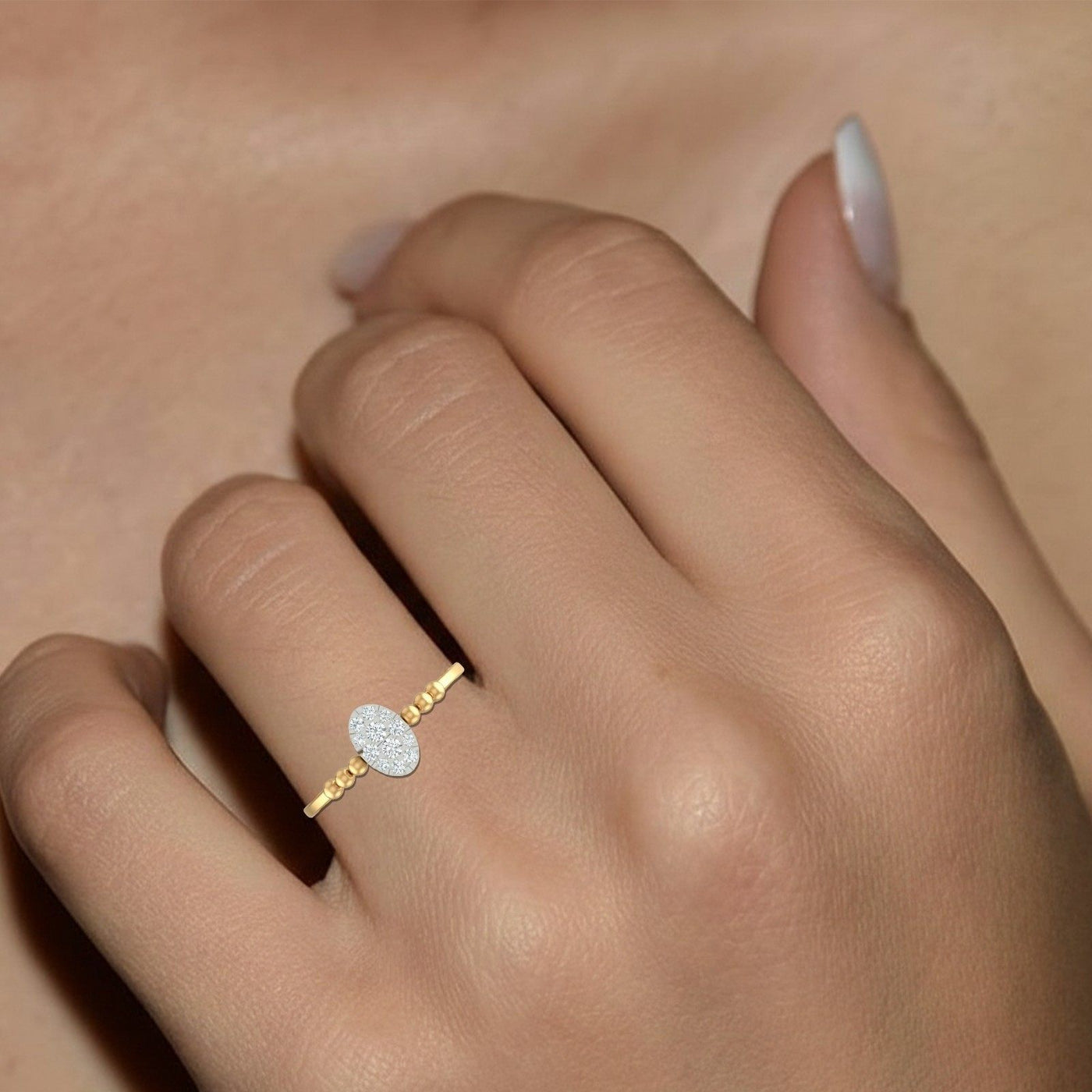 Gold ring with a diamond on a person's finger against a neutral background