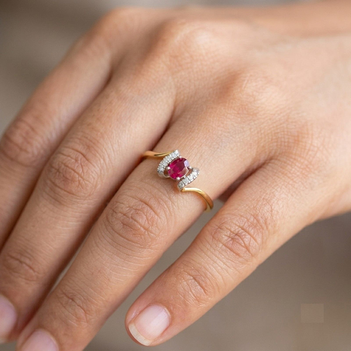 Close-up shot of a gold and diamond with oval ruby gemstone setting ring