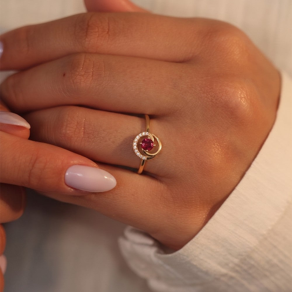Gold ring with a red gemstone on a person's finger