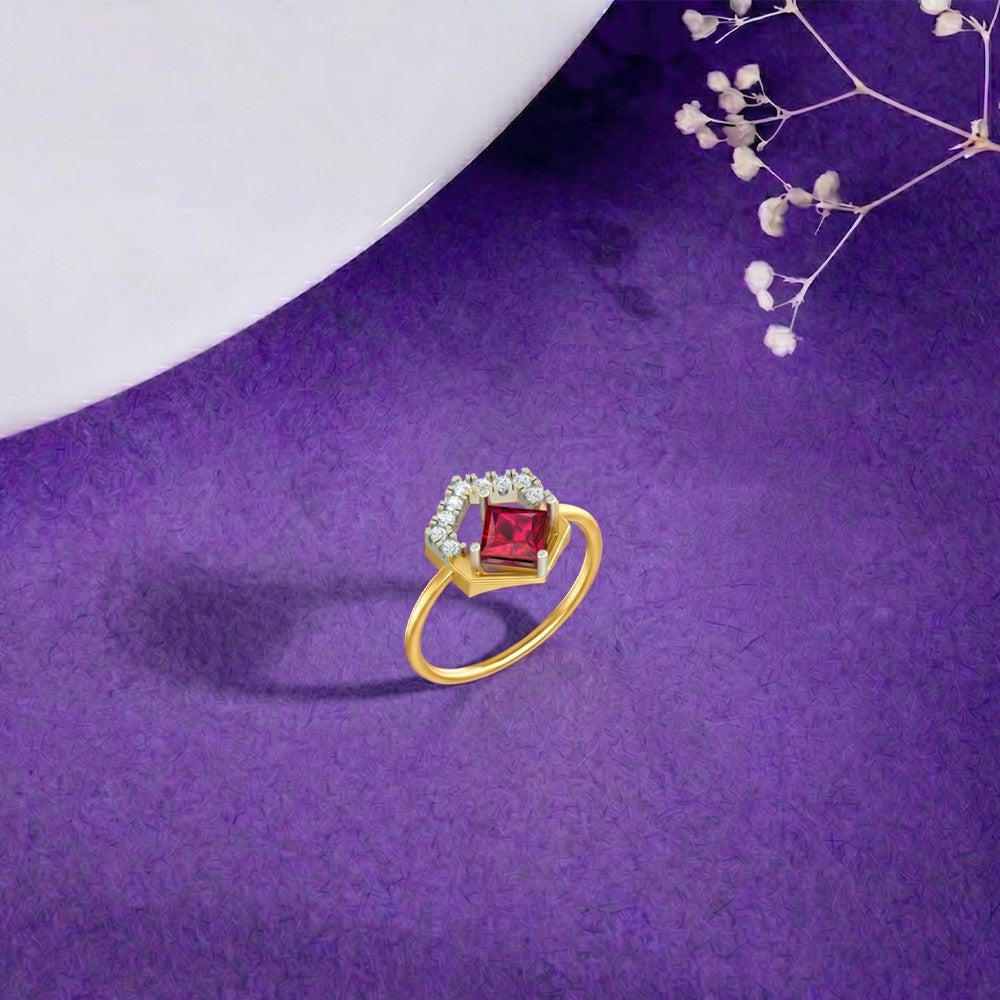 A gold ring with a square-cut red center stone and a halo, displayed on a textured purple surface.