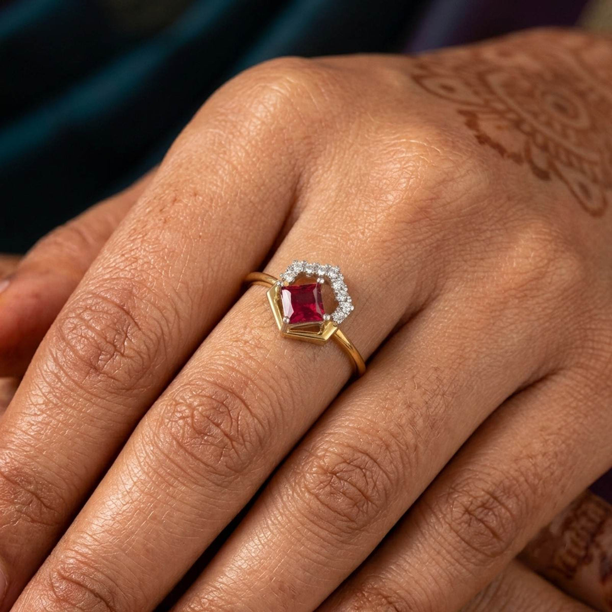 Gold ring with a ruby gemstone on a hand against a white background
