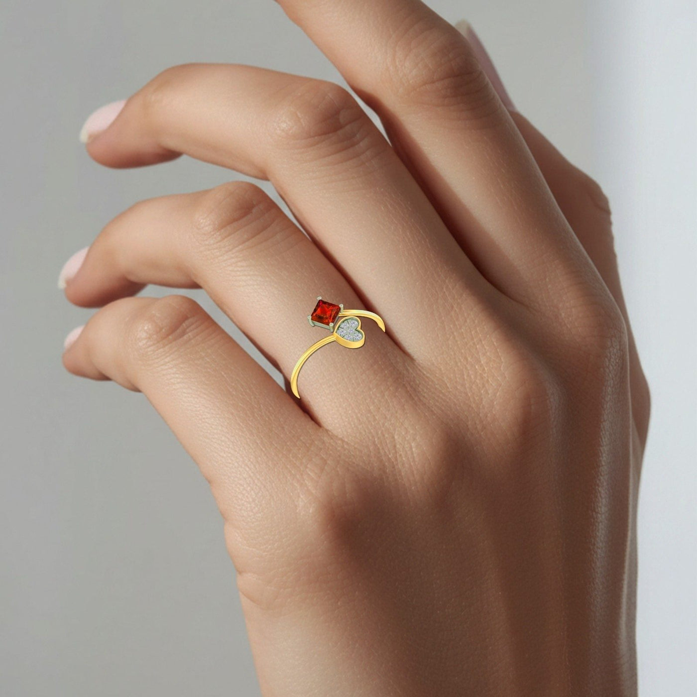 Gold and diamond with square-shaped ruby gemstone setting on a person's finger.
