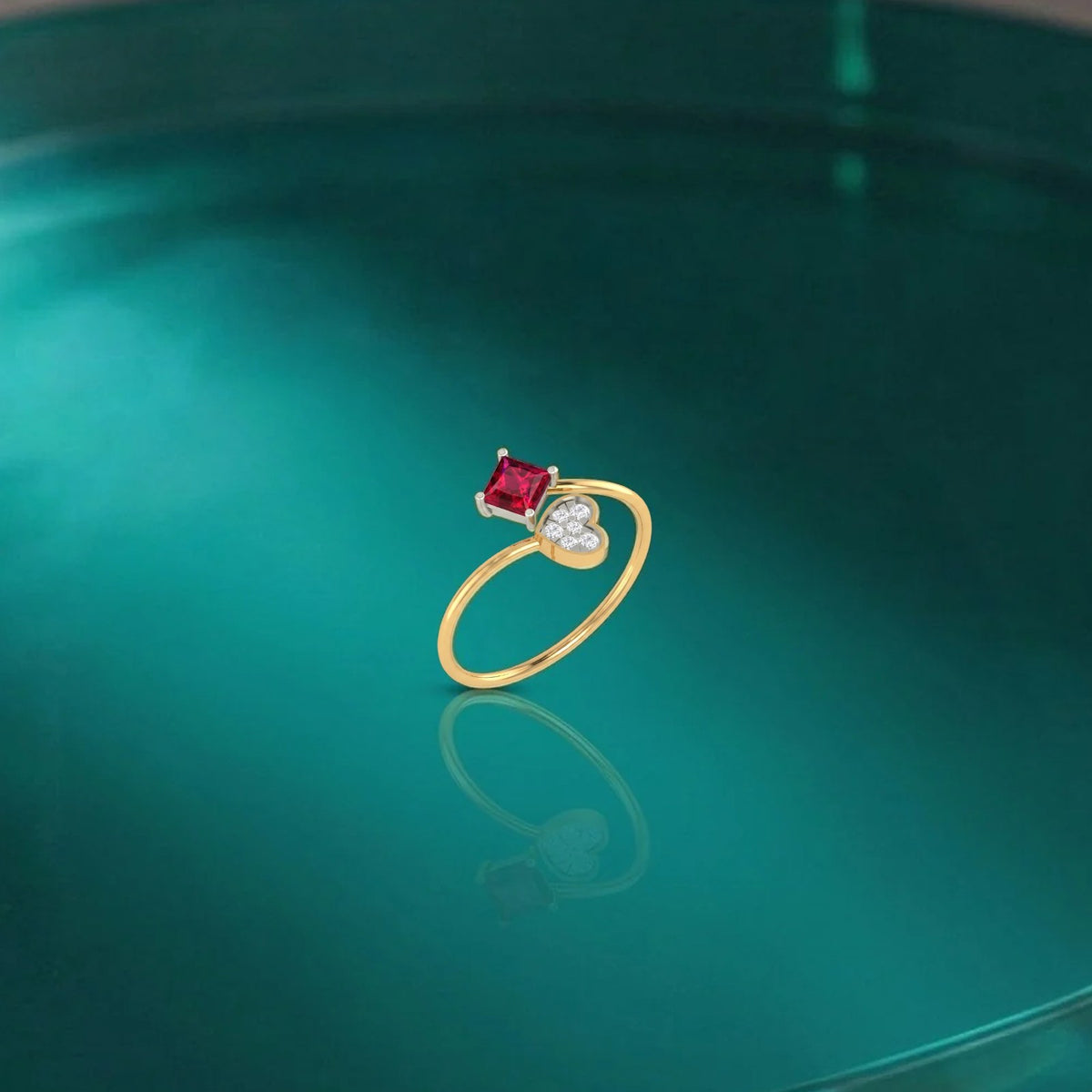Gold and diamond ring with a ruby gemstone on a reflective green surface