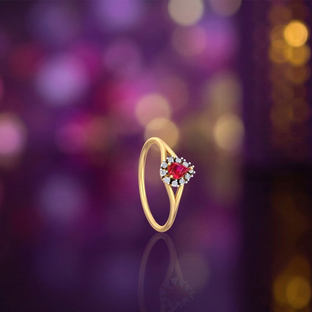 Gold and diamond with teardrop ruby gemstone setting on a reflective surface.