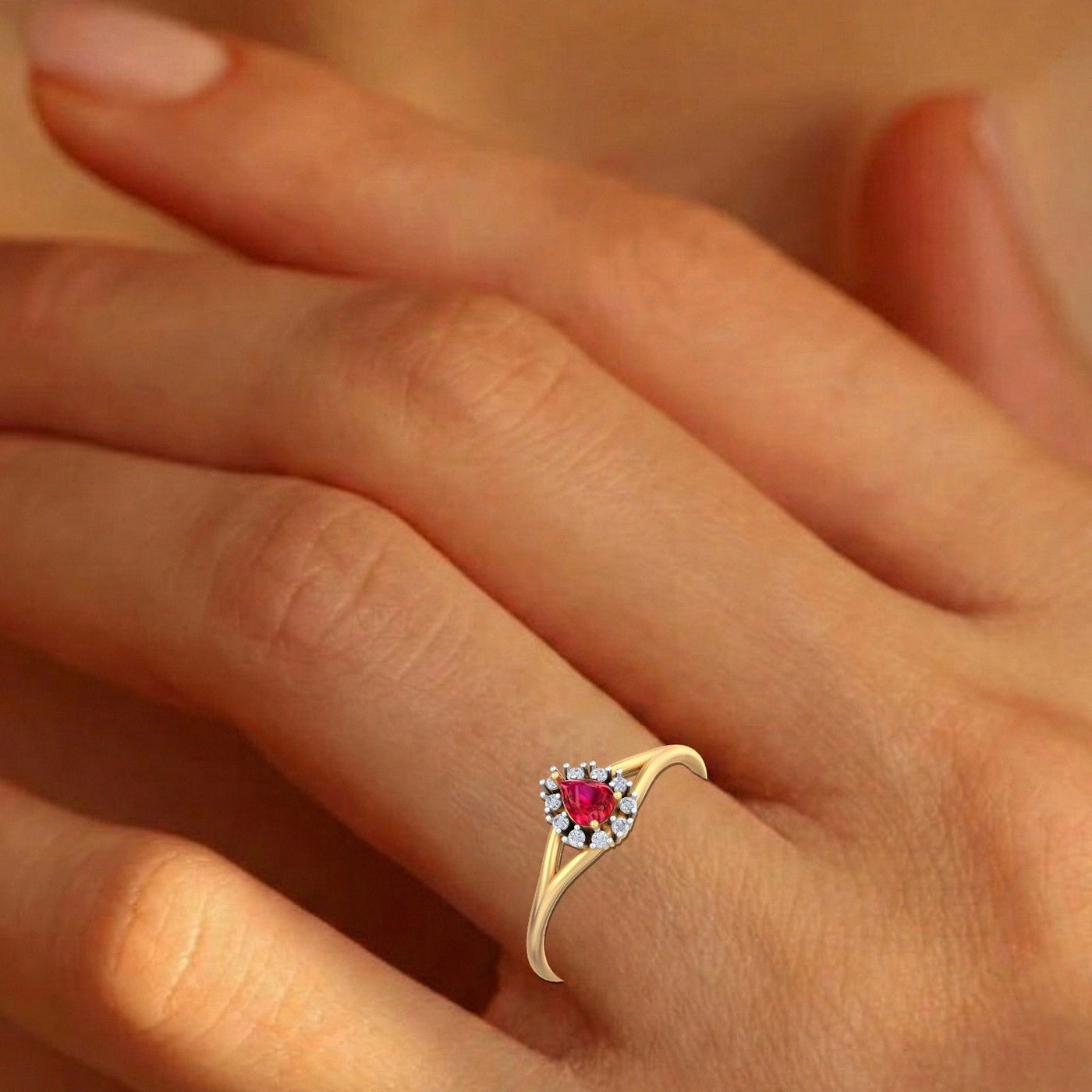 Gold and diamond with teardrop ruby gemstone setting on a person's finger.