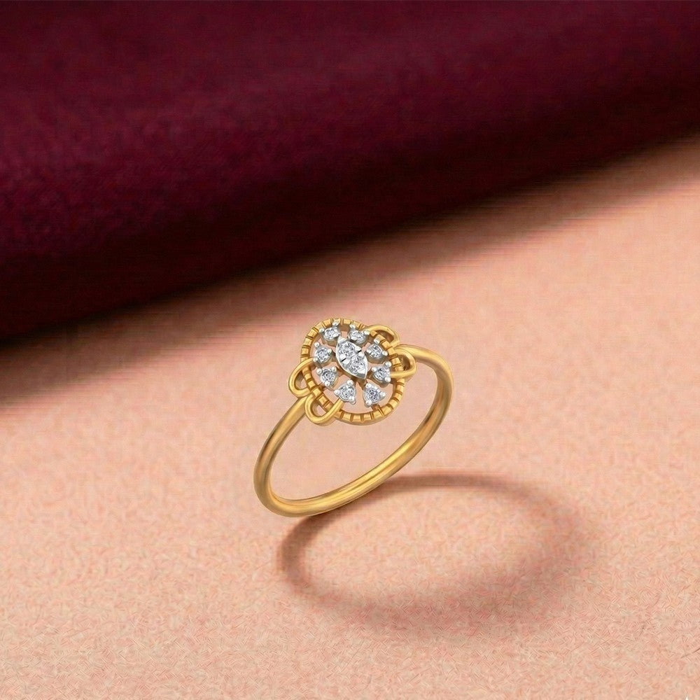 Gold ring with a floral-design cluster, set against a pink surface.