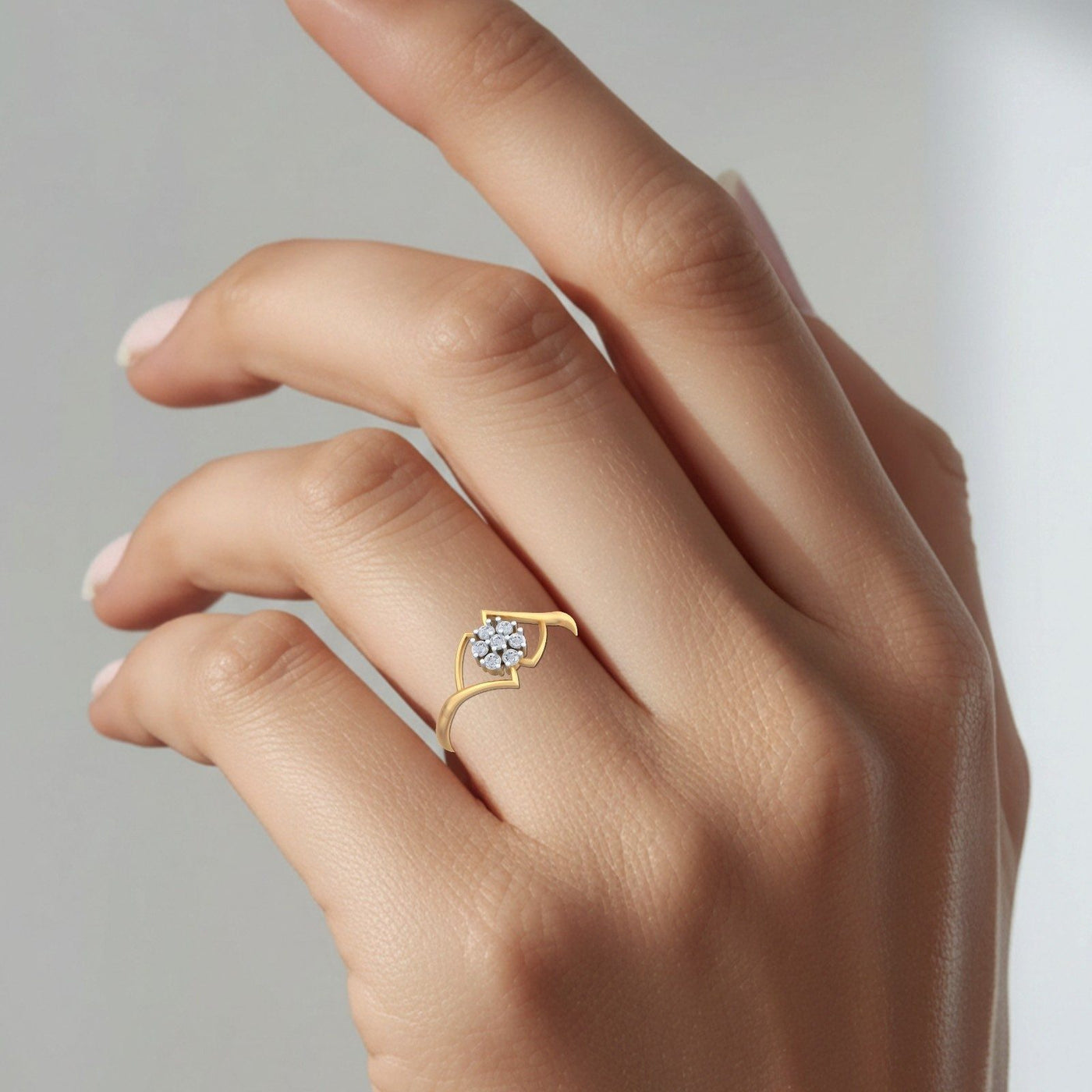 Gold ring with a diamond on a hand against a neutral background.