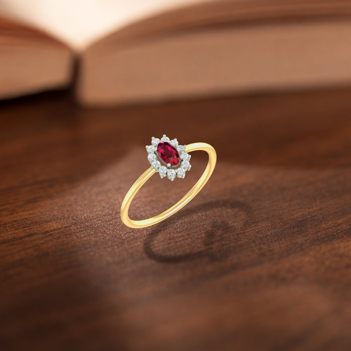 Gold and diamond with oval-shaped ruby gemstone setting on a wooden surface.