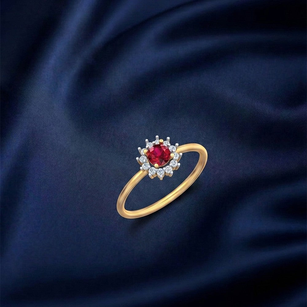 Gold and diamond with ruby gemstone setting on a blue fabric surface.