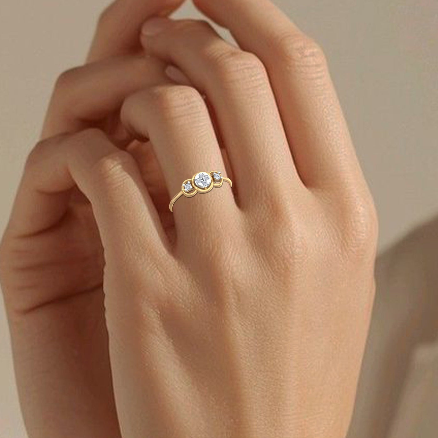 Gold ring with three diamonds on a hand against a beige background