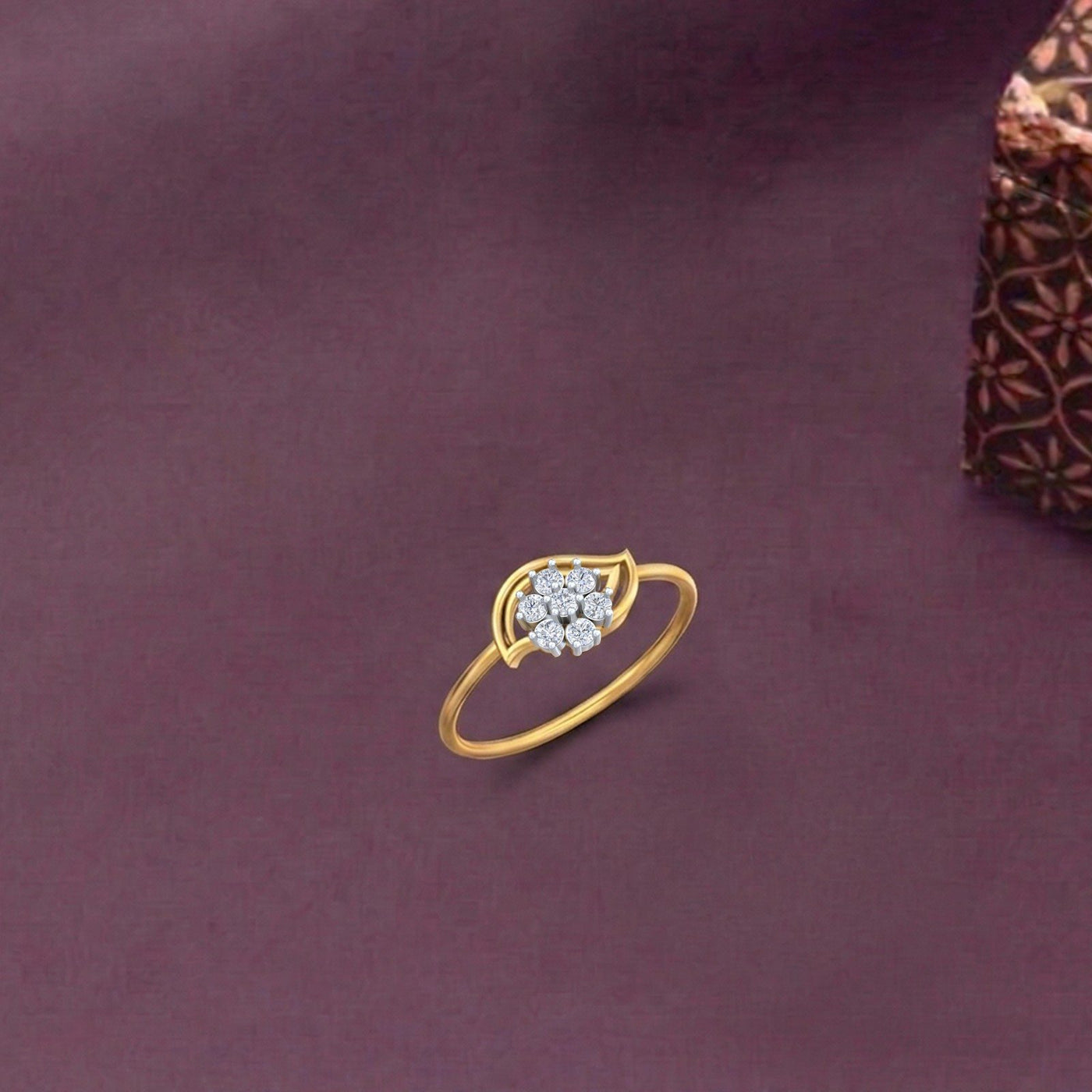Gold and diamond with floral cluster setting on a fabric surface.