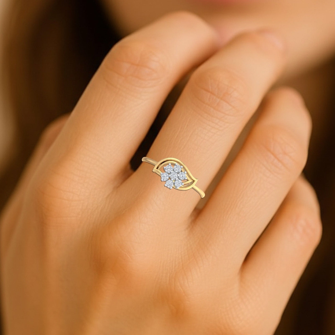 Gold ring with a diamond floral design on a hand against a blurred background