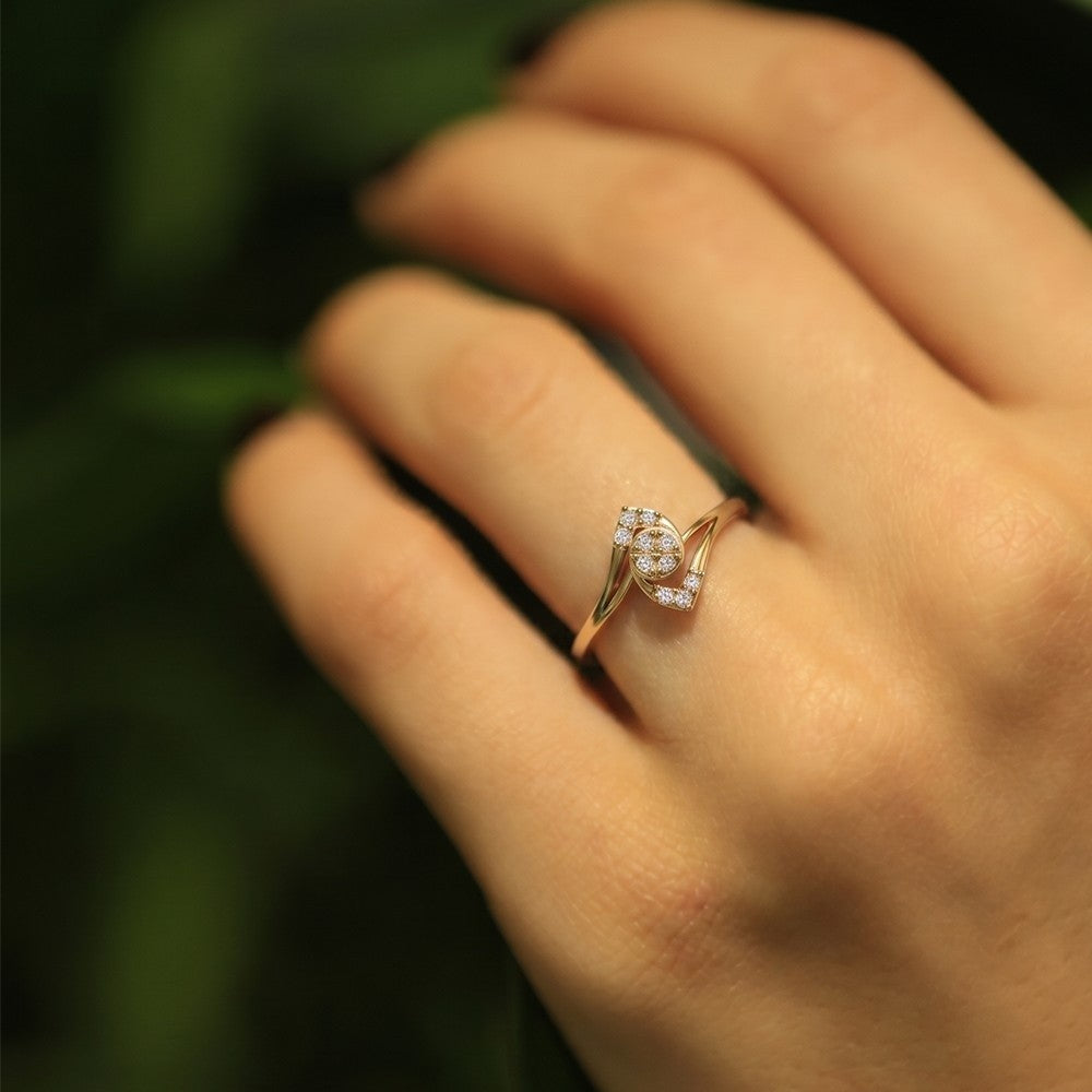 Gold ring with diamonds on a person's finger against a blurred green background