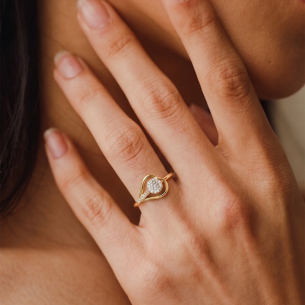 Close-up of a hand wearing a gold ring with a diamond on a neutral background