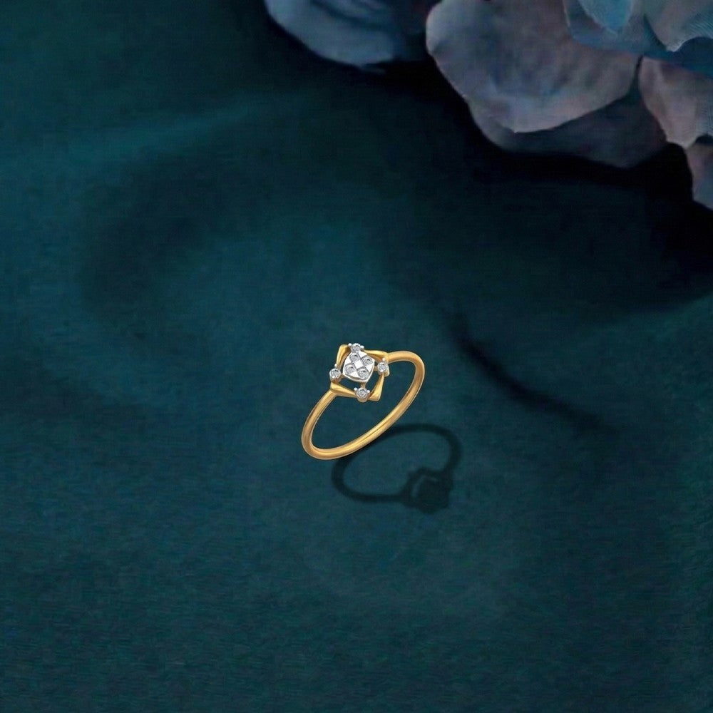 A gold ring featuring a geometric openwork design with a central cluster, shown on a teal surface.