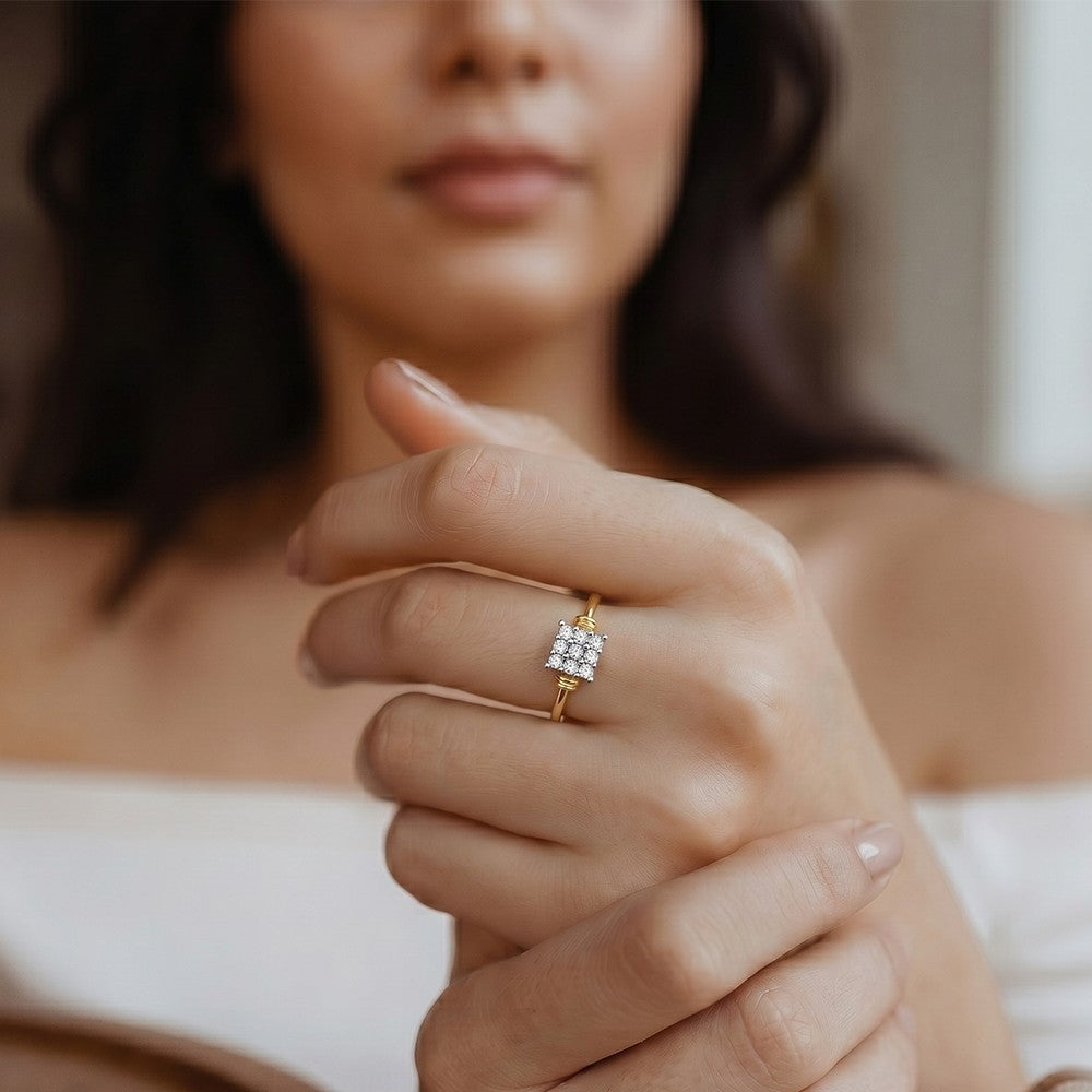 Close-up of a hand wearing a gold ring with a diamond, blurred background