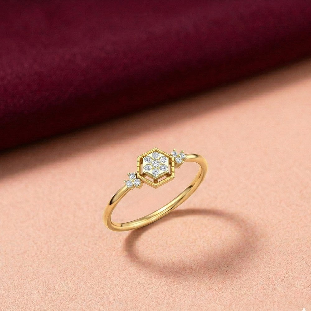 Gold ring with diamond accents on a pink fabric background