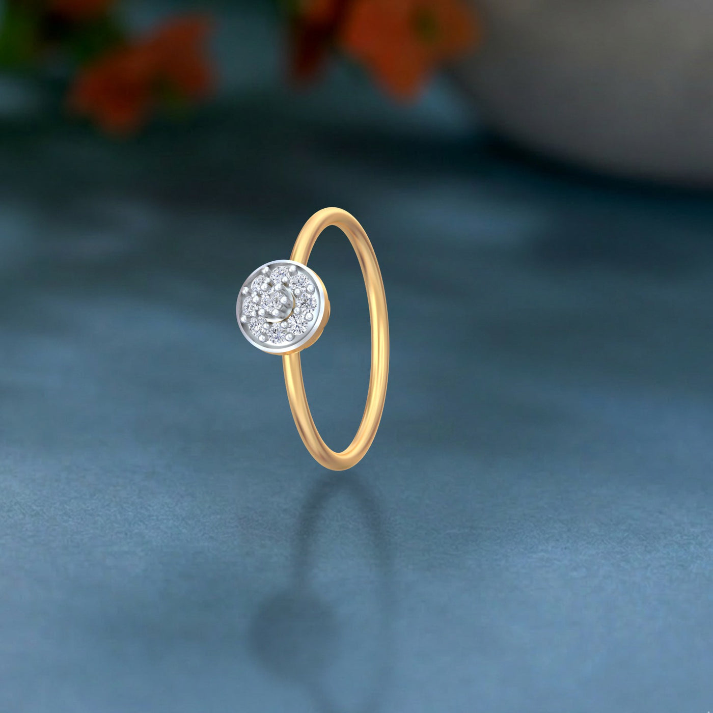 Gold and diamond with circular cluster setting on a teal surface.