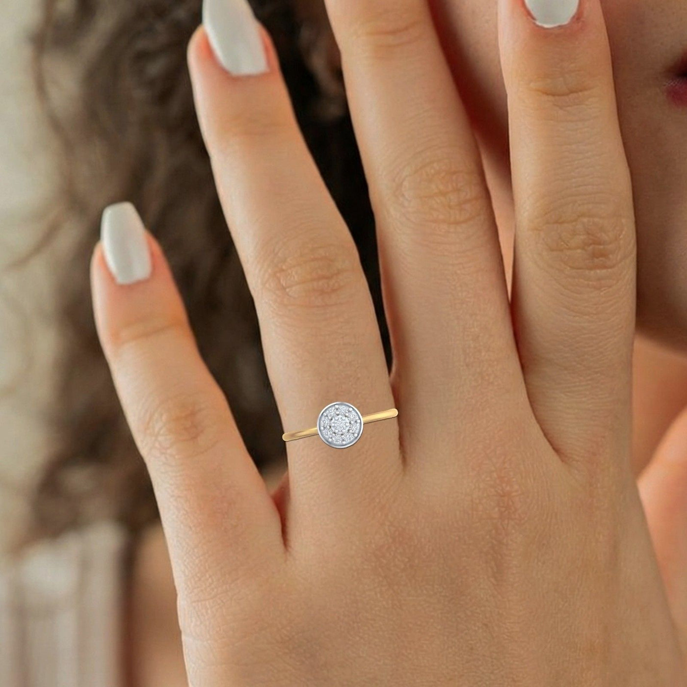 Gold ring with a diamond on a person's finger against a blurred background