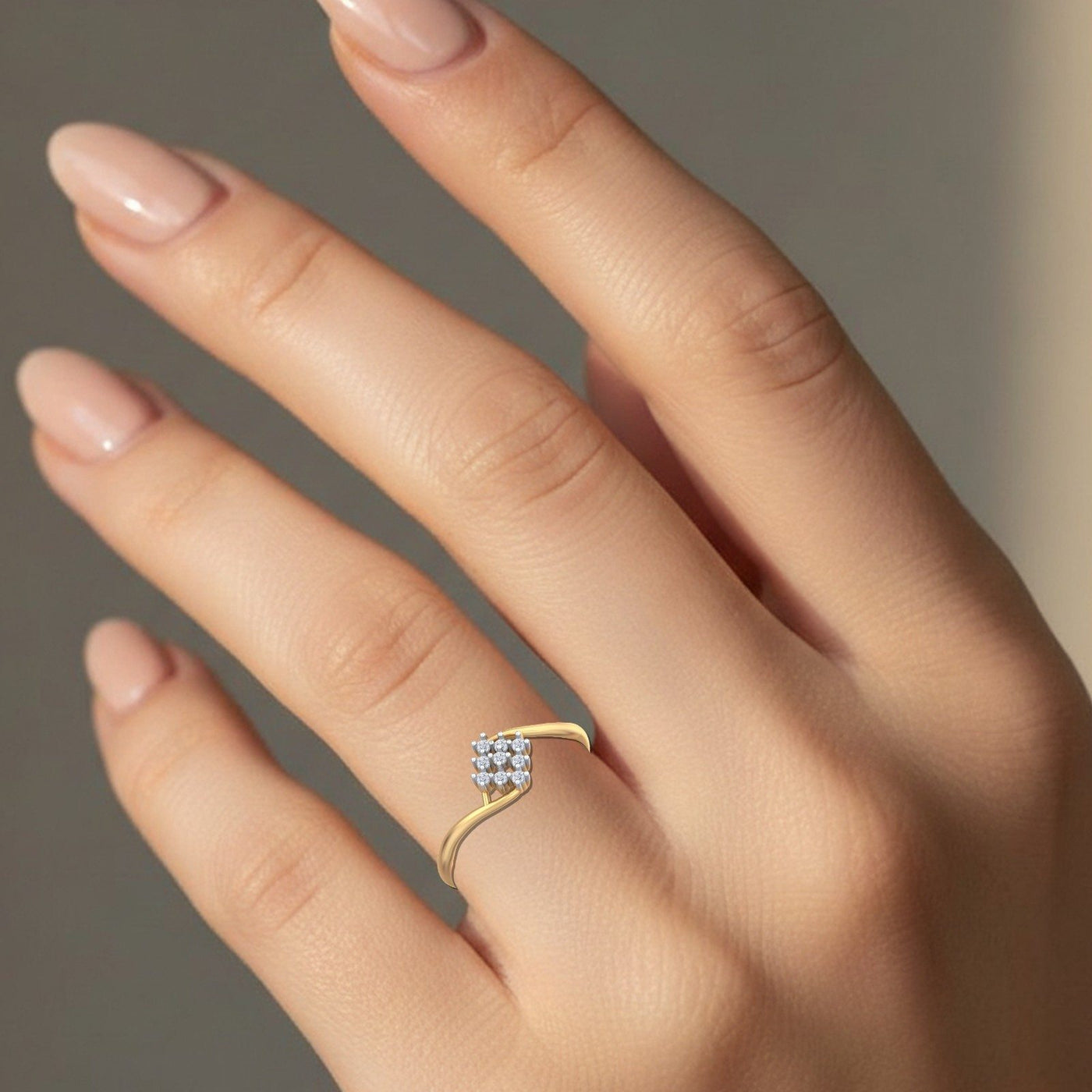 Gold ring with a diamond cluster on a hand against a neutral background