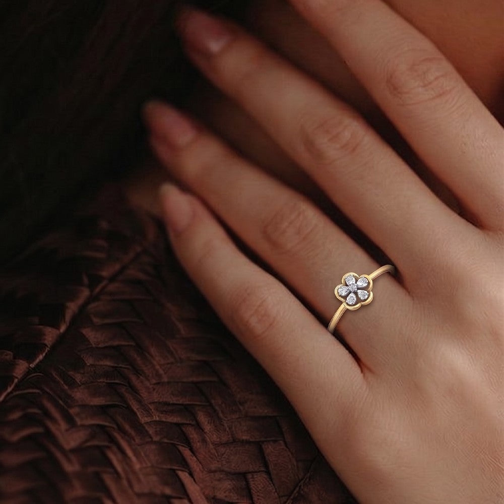 Gold ring with a floral design on a hand against a textured brown background