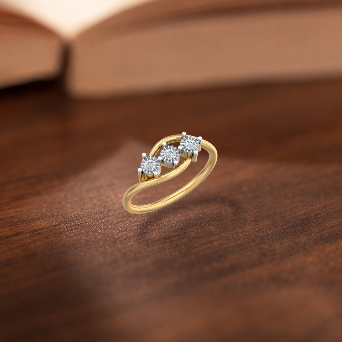 A gold ring with three clear diamond, resting on a dark wooden surface.